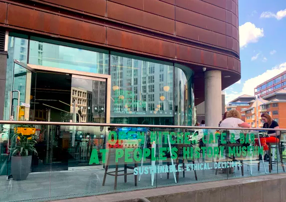 The outside entrance to the Open Kitchen cafe with seating and a balcony