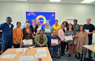 Group of smiling people from a range of different backgrounds smiling in front of a presentation slide at the end of a workshop