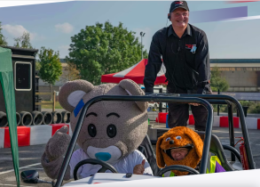 Racing car with smiling driver and coach standing