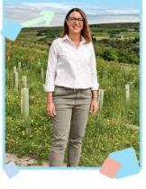 Karen the founder smiling with an arrow pointing up and standing in front of a wide green meadows
