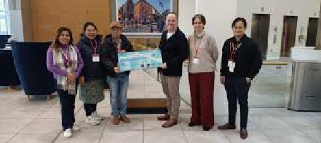 People stood for a picture holding a cheque