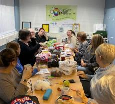 Table of women laughing, drinking hot drinks, and taking part in crafting activities