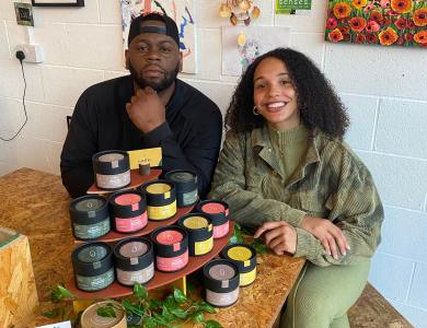 Founder and friend smiling whilst displaying their skincare products displayed 