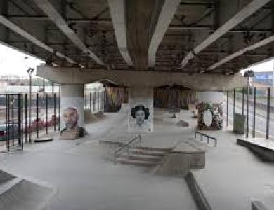 A picture of a large skatepark with ramps and graffiti art on the wall
